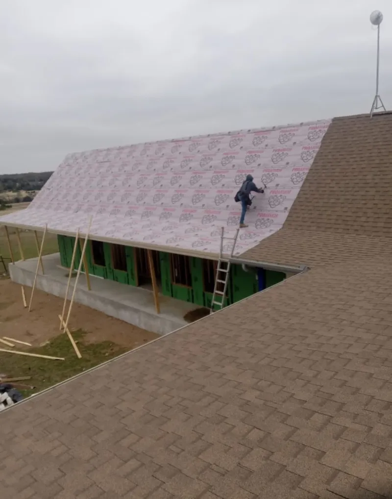 Worker preparing underlayment for a metal roof installation in Buffalo